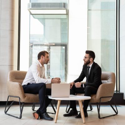 Businessmen discussing deal, sharing startup ideas, business partners negotiations or job interview in modern office with panoramic windows, colleagues talking, working on project together